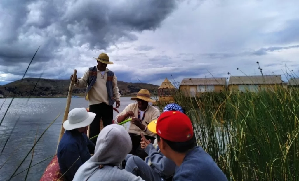 Uros men showing how to fish and cut reeds